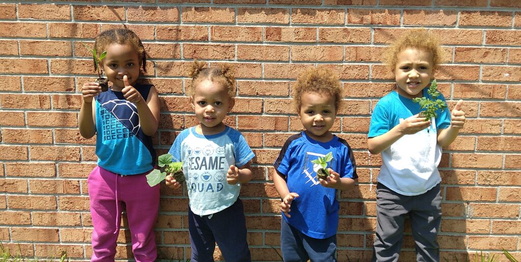 Mine and my best friend's kids holding seedlings that were started in the best seed starting medium – peat pellets.